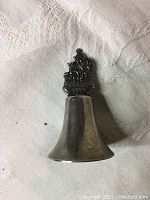 Front view of the small silver Aruba souvenir bell showing detailed decorative handle with palm tree, person, and 'Aruba' text.