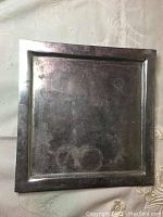 Photo of square pewter tray showing overall surface and shape with visible light scratches and patina