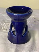 Blue ceramic aroma lamp with round dish top and triangular cut-out base openings.