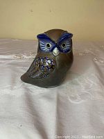 Front view of the owl figurine showing metallic body and blue painted face detail