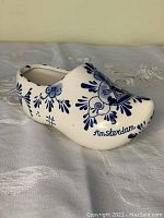 White ceramic clog with blue floral and windmill decoration and 'Amsterdam' text