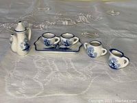 Full set displaying teapot, two cups on tray, sugar bowl, and creamer