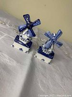 Pair of ceramic Dutch windmill salt and pepper shakers with blue and white glaze, shown together.