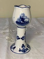 Side view of white Delft porcelain tulip candle holder with blue hand-painted windmill and floral designs on a glossy finish