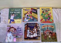 Group photo showing six Jewish children's books arranged on white cloth background.