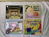 Four children's books laid out: The Very Crowded Sukkah, Ella's Trip to Israel, The Better-Than-Best Purim, Grandma Rose's Magic
