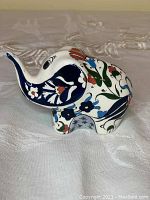 Side profile of the ceramic elephant showing colorful floral and leaf patterns and glossy glaze finish