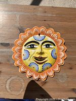 Top-down photo showing the full sun wall decor with a smiling face and floral patterns