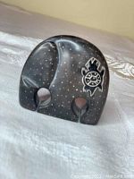 Front view of black limestone elephant figurine showing painted white dots and turtle design on side.
