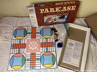 Full view of board game laid out with box, instruction sheet, playing pieces, and dice visible.