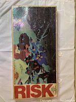 Top view of Risk game box showing detailed world conquest map with territories outlined and colored.