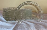Set of six clear glass half moon shaped plates stacked, showing their curved ridged edges and oval form.