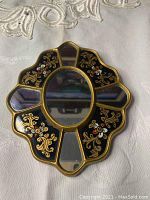 Top-down view of the front of the cross-shaped small mirror showing the decorative painted black glass sections with gold floral and ornamental details, and five mirrored glass insets.