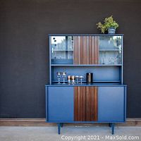 Photo of a blue painted wood cabinet with wood accent panels and glass doors on top, illustrating the paint finish.
