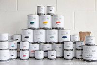 Photo showing a variety of Mango Paint cans in multiple sizes and colors, arranged in a pyramid shape against a plain background.