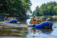 Group rafting on Ottawa River with blue inflatable Wilderness Tours rafts and paddles