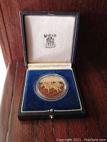 Gold-tone circular medal inside a blue velvet-lined case, case lid embossed with Royal Hong Kong Jockey Club crest.