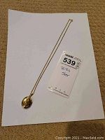 Overall view of the necklace with locket placed on white paper showing chain and pendant.