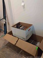 Three cardboard boxes filled with CDs and VCDs.