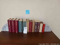 Full view of ten Chinese books flanked by two marble bookends on wood surface