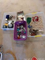 Three baskets on carpet containing assorted jewelry and boxes