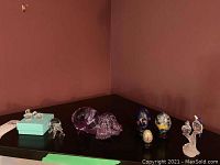 Wide angle image showing glass animal figurines including a pink elephant, clear glass animals, and decorative eggs on display.