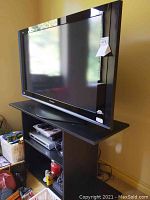 Panasonic 42 inch VIERA HDTV on black media stand with Electrohome DVD player and accessories visible on shelves below.