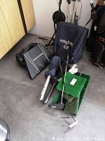 Overall view of golf practice equipment including bag, clubs, practice green, and push cart