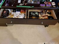 Two open drawers in dark wood console showing boxes, jewelry and sunglasses