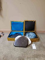 Two yellow floral patterned boxes, one open showing blue ceramic plate, the other open showing volcanic stone on black metal tray