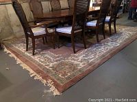 Full view of the large plush wool area rug underneath a dining table and chairs, showcasing its size, color, and fringe detail.