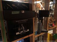 Photo showing boxed Magic Decanter Deluxe Aerator Set, black lined wine box, and Sodastream aerator on a shelf in basement setting