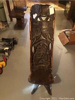 Full front view of the carved wooden chair showing elephant top rail, forest scene backrest, seat and legs