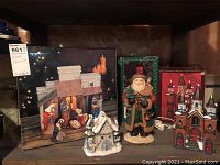 Four items displayed on shelf: nativity set in box, 10-inch Santa figure, hand-painted porcelain church in packaging, ceramic church with cavity for tea light