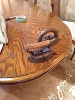 Pair of vintage sad irons placed on wooden table, showing wood grain and iron bases with handles