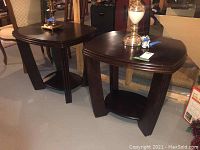 Pair of dark wood end tables with lamps placed on top, showing front and angled positions to highlight design and condition.