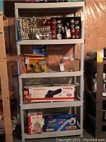 Full view of the beige resin shelving unit showing five shelves stacked vertically. The shelving is loaded with various boxes and items used for context but contents are not included.