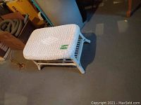 Top angled view of white wicker table showing woven top, rectangular shape and legs.