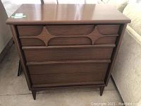 Front view of the Mid-Century Modern wood dresser showing the distinct carved drawer fronts and tapered legs.