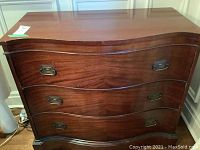 Front view of mahogany buffet showing three serpentine drawers and brass bail handles