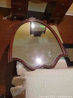 Large decorative antique mirror with carved wood frame and beveled glass on white fabric with wood floor background