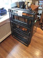Folded black metal double bedframe leaning against wall next to window and radiator, showing compact framework and metal structure.