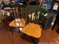 Two wooden chairs with natural wood seats and green-painted backs and legs shown from front angle.