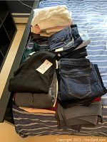 Two stacks of folded tops and jeans on striped bedding, showing overall contents