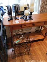Photo showing composite giraffe bookends, metal candleholders with pillar candles on a wooden surface, and metal wine rack below.