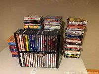 Stacks of DVDs and VHS tapes arranged on a table featuring assorted titles and genres.