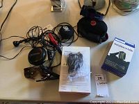 Overview of lot on tabletop showing headphones, tablet box, car holder, sunglasses, lamp