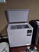 White chest freezer with lid open showing interior and hanging basket