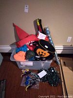 Small assortment of Halloween decor including hat, costume pieces, pumpkin bucket, and lights