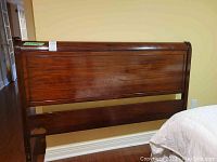 Front-right angle view of the John Wanamaker vintage solid wood headboard showing paneled wood and minor scratches.